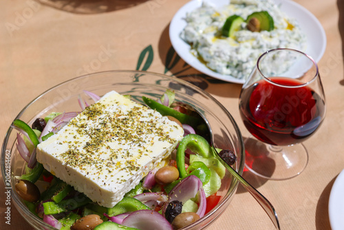 Photography Traditional Greek salad with feta cheese, tzatziki and red wine in Crete, Greece