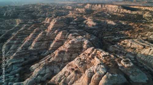 Expansive aerial view of layered sandstone formations and rugged desert landscape under a hazy sky