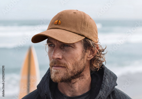 Man at the Ocean Wearing a Cap with Logo Mockup