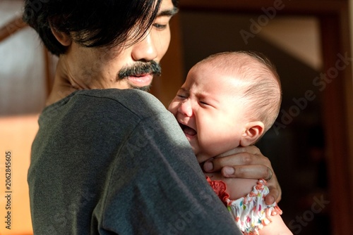 Foto Father comforting crying baby tenderly.