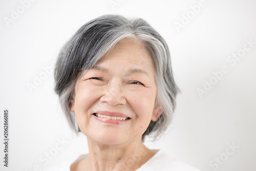 Foto Close-up of an elderly woman (senior) with gray hair against a white background;