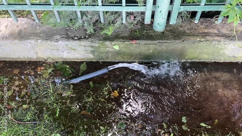 Water vigorously squirts out of a rubber hose, flooding the nearby area