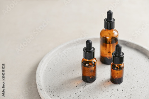 Natural skincare and beauty treatment concept with amber glass cosmetic containers arranged on a round tray.