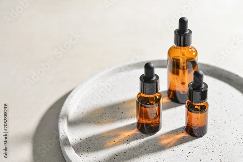 Natural skincare and beauty treatment concept with amber glass cosmetic containers arranged on a round tray.