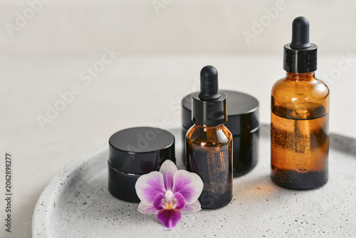 Natural skincare and beauty treatment concept with amber glass cosmetic containers arranged on a round tray.