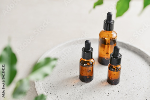Natural skincare and beauty treatment concept with amber glass cosmetic containers arranged on a round tray.