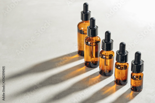 Amber glass dropper bottles of different sizes arranged in ascending order from smallest to largest on light background.