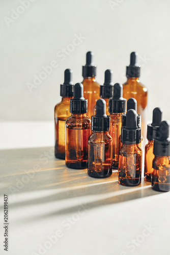 Amber glass dropper bottles of different sizes arranged in ascending order from smallest to largest on light background.