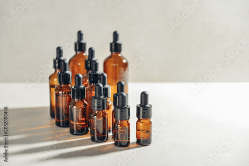 Amber glass dropper bottles of different sizes arranged in ascending order from smallest to largest on light background.