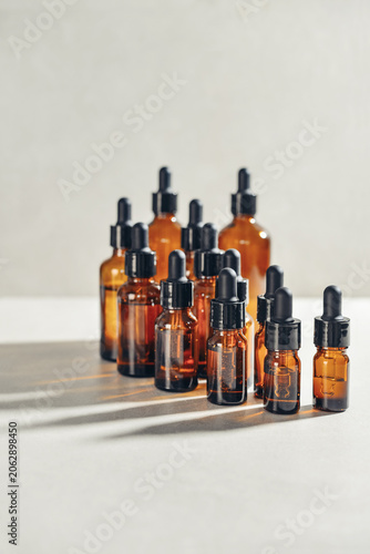 Amber glass dropper bottles of different sizes arranged in ascending order from smallest to largest on light background.