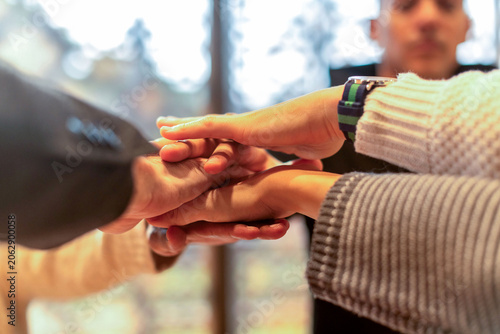 Schilderij op canvas Diverse group of hands stacked in a teamwork gesture indoors.