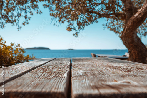 Empty wooden table top at a seaside restaurant with beautiful ocean view on a sunny day