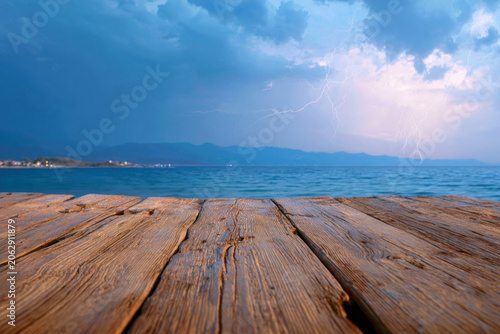Empty wooden table top with dramatic ocean view and storm clouds forming in the distance