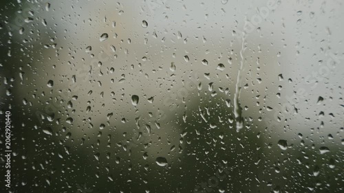 Large raindrops on the window during the rain against the background of the city