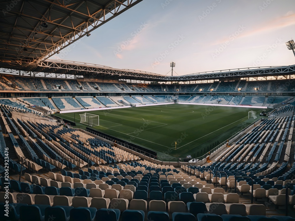 Naklejka premium Empty large stadium with green field under cloudy sky