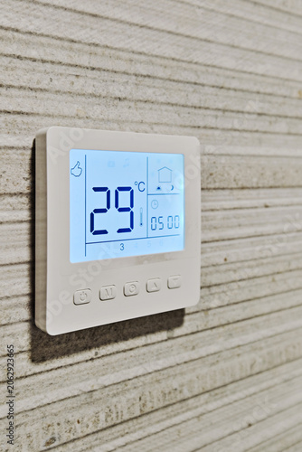 Smart digital thermostat installed on modern textured wall, closeup