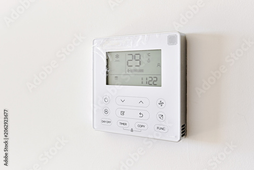 Close up of modern wall-mounted digital thermostat on white wall background. Smart home , modern technology