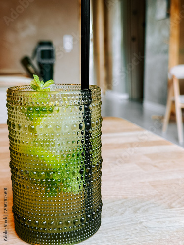 Refreshing green drink in unique textured glass on light wooden table