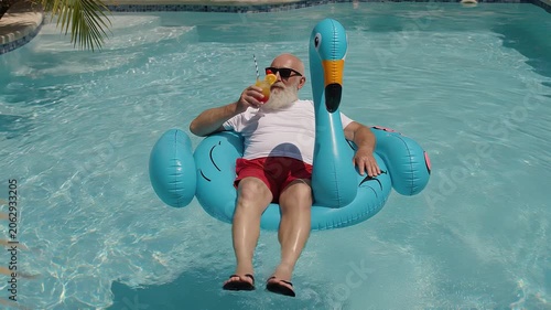 Man relaxing on a flamingo-shaped inflatable float in a swimming pool while enjoying a cold drink, capturing summer leisure, vacation, and resort lifestyle.