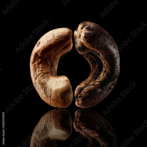 Close-up of a perfectly roasted light and dark cashew nut with a reflective surface on black background
