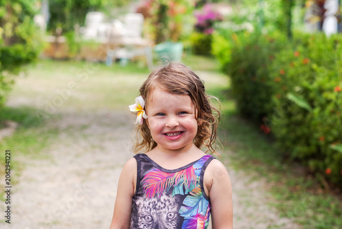 summer portrait of a cute little girl. The child smiles at the camera. A little girl with blonde hair makes faces