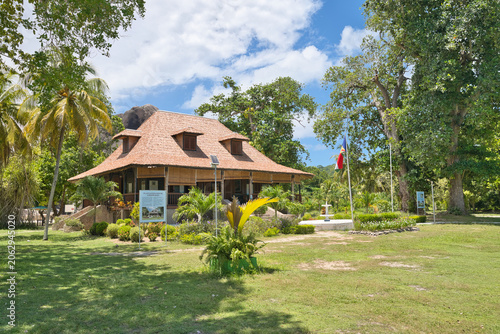 La Digue, Seychelles, 01.06.2026, Beautiful view of the historic Grand Kaz colonial heritage plantation house at L'Union Estate, featuring a garden fountain and national flag under a blue sky