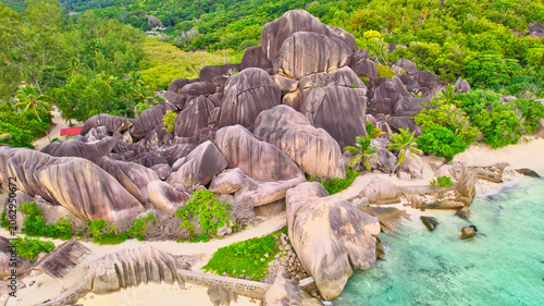 Фотография High-angle drone shot of the world-famous Anse Source d'Argent beach in Seychelles, showcasing spectacular weathered granite rocks, white sand, lush palms, and clear turquoise water