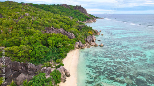 Foto High-angle drone shot of the world-famous Anse Source d'Argent beach in Seychelles, showcasing spectacular weathered granite rocks, white sand, lush palms, and clear turquoise water