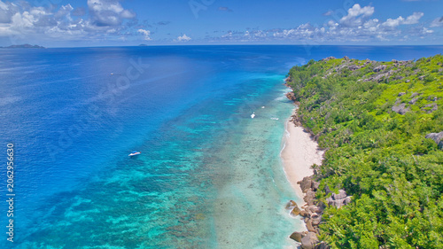 Φωτογραφία High-angle drone view of Little Sister Island, Seychelles, showcasing an excursion boat anchored in turquoise water next to a white sandy beach and lush green forest