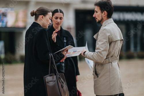 Vászonkép Three business professionals review charts and papers while standing outdoors