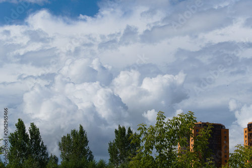 Cumulus clouds over trees and houses