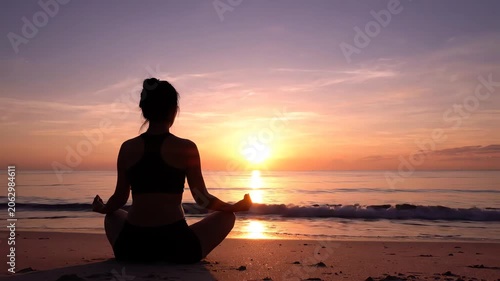 Silhouette of a woman meditating on a beach at sunset with warm, serene colors and a calm atmosphere.