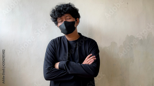 Young Man with Face Mask and Closed Eyes Standing with Crossed Arms