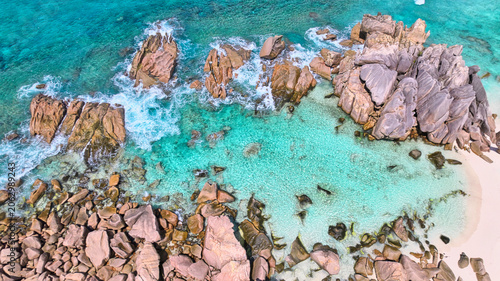 Spectacular drone shot of the famous natural swimming pool enclosed by giant granite rocks on the white sandy beach of Anse Cocos, La Digue island, Seychelles. Pristine tropical paradise