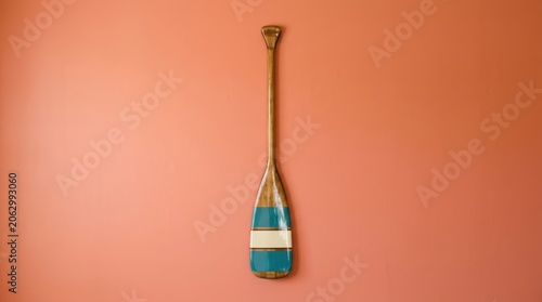 Decorative Wooden Paddle Hanging on a Vibrant Coral Wall.