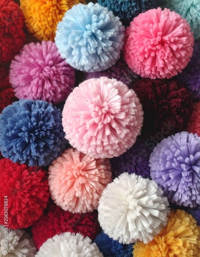 A vibrant collection of colorful, fluffy, spherical pom-poms densely packed together