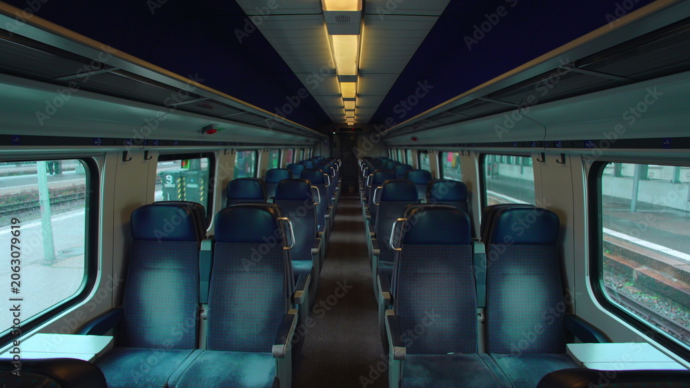 Fototapeta premium Empty commuter train interior before departure with aligned seats and quiet symmetry evoking stillness anticipation routine travel pause and calm urban transit atmosphere