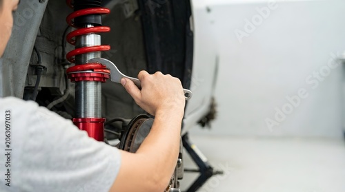Professional Mechanic Adjusting Red Car Suspension Performance Coilover Sport Spring in Workshop