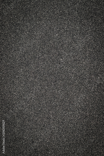 Black texture seen up close shows a rough surface with small particles and grains in a uniform setting during daylight
