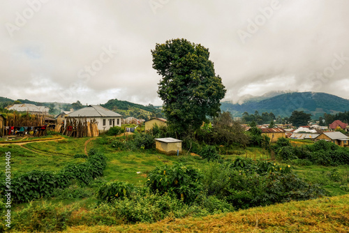 Scenic Rural Landscape of Mbeya Town, Tanzania with Houses and Lush Green Hills Under a Cloudy Sky