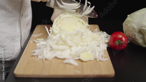 Hands chopping cabbage on a wooden cutting board