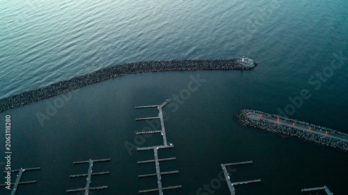 Tableau sur toile A striking top-down drone photograph looking down at the stone breakwater walls and illuminated promenade pier protecting empty marina boat slips in the dark, calm waters of Bronte Harbour at dawn