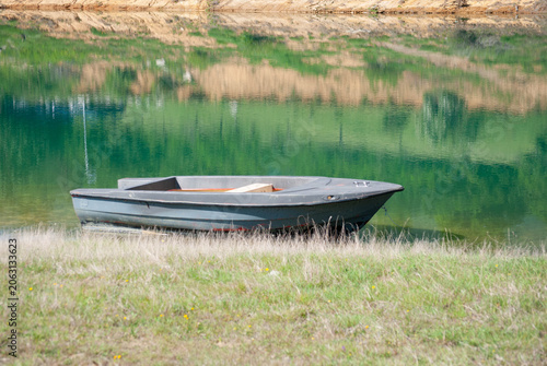 Foto Rustic wooden boat resting on the peaceful shore of Rama Lake, Bosnia and Herzegovina, surrounded by calm water and scenic natural beauty
