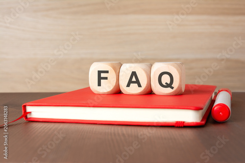 Wooden cubes with FAQ text on a red notebook