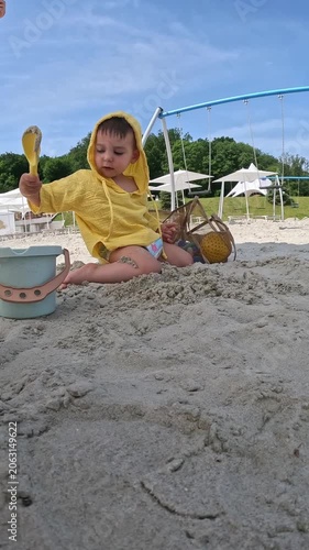 Toddler playing in sand with bucket and shovel
