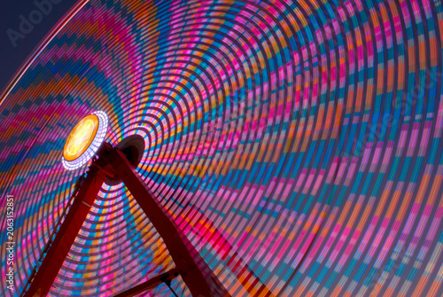 Long exposure ferris wheel spinning colorful lights at night
