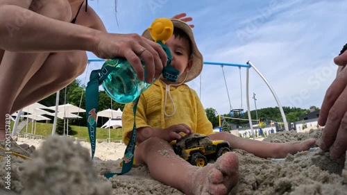 Toddler playing in sand with toy truck at playground