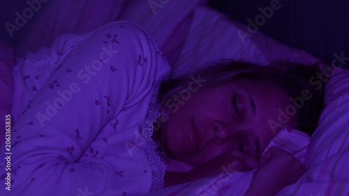Young woman sleeps in bed at night and suddenly twitches from hypnagogic jerks. Sleep disturbance, involuntary movement and nervous system concept