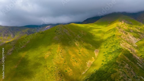 descending drone hyper lapse of green mountain slope under storm cloud in Kyrgyzstan