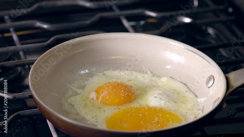 Frying eggs in a pan. Yellow yolks glisten over a lightly cooked white.